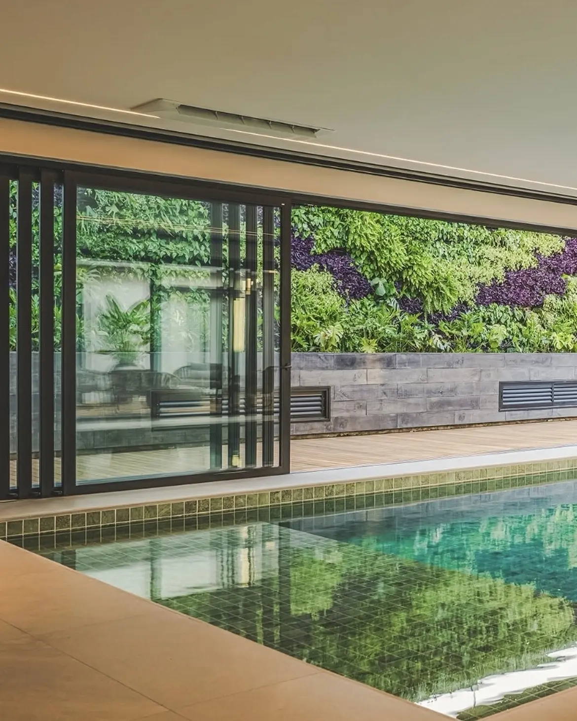 Piscina coberta com portas de correr e jardim vertical
